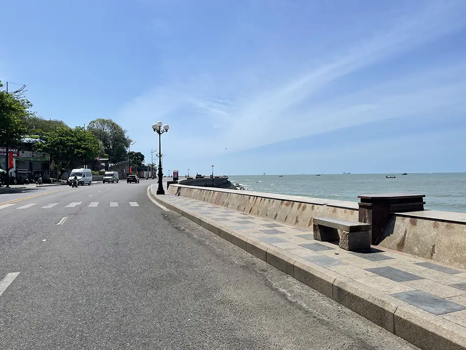 Empty coastal road curving along the Vung Tau cape beside the sea.