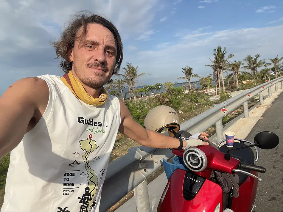 Yuriy Malykh taking a selfie beside his electric scooter during the Vietnam crossing journey.