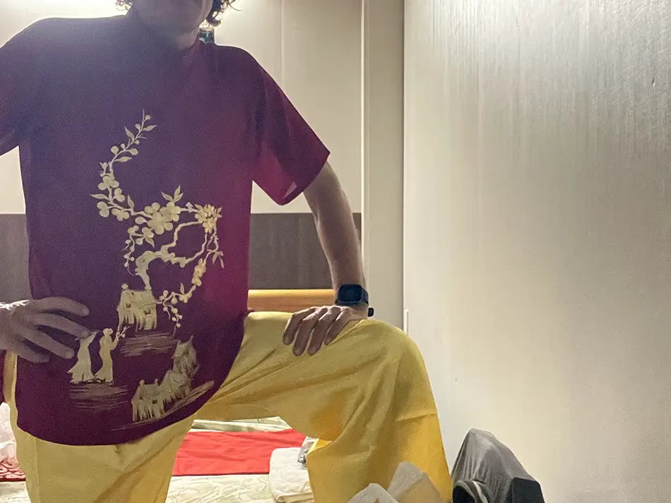 A traveler wearing a bright red traditional male Ao Dai.