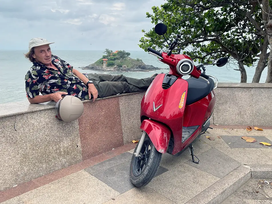 Traveler with electric scooter in front of Hon Ba island in Vung Tau