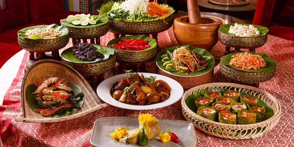 A vibrant display of the best food in Cambodia, featuring classic dishes like amok trey, khor sach chrouk, bok l’hong papaya salad, seafood, and traditional Cambodian desserts on a festive table setting