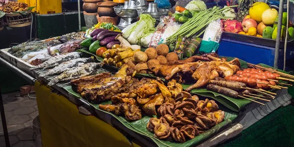 Best food in Laos: night market stall with grilled chicken, sausages, salt-crusted fish, fresh vegetables and seafood.