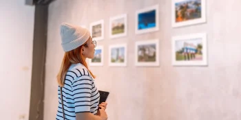 Visitor viewing framed artwork in a modern exhibition space, representing the experience at the best art galleries in Vietnam.
